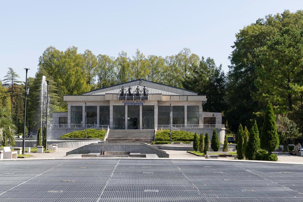 Cultuurcentrum met moderne architectuur en groene omgeving, inclusief fonteinen en beplanting.